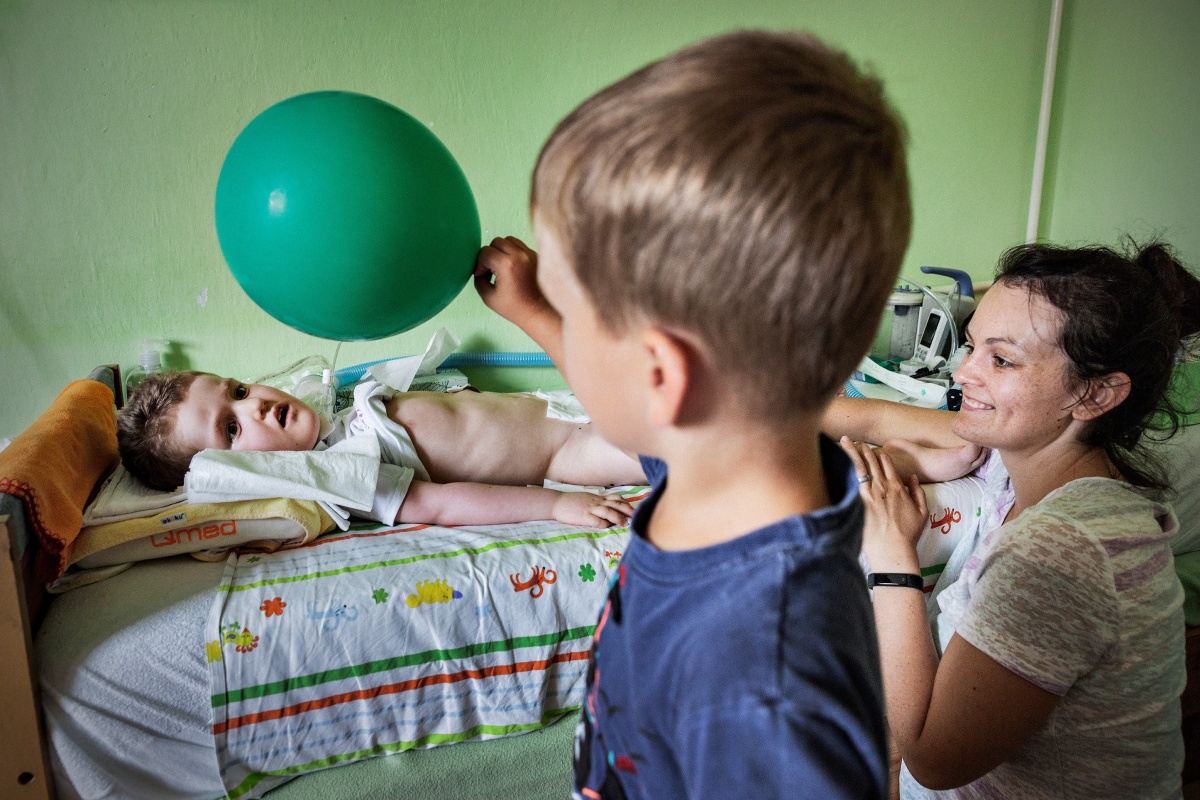 Matka a dítě při péči v nemocničním prostředí, doprovázené dalším dítětem
